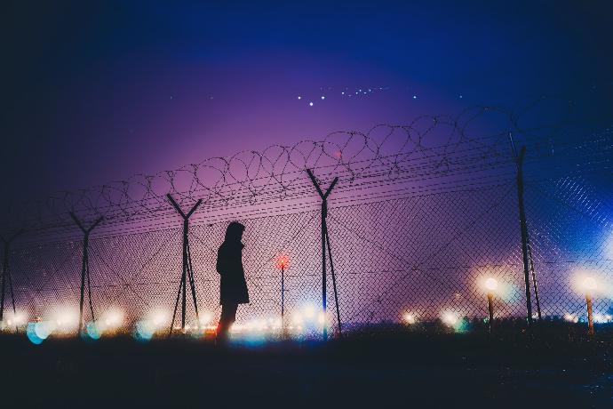 person's silhouette standing near chain link fence